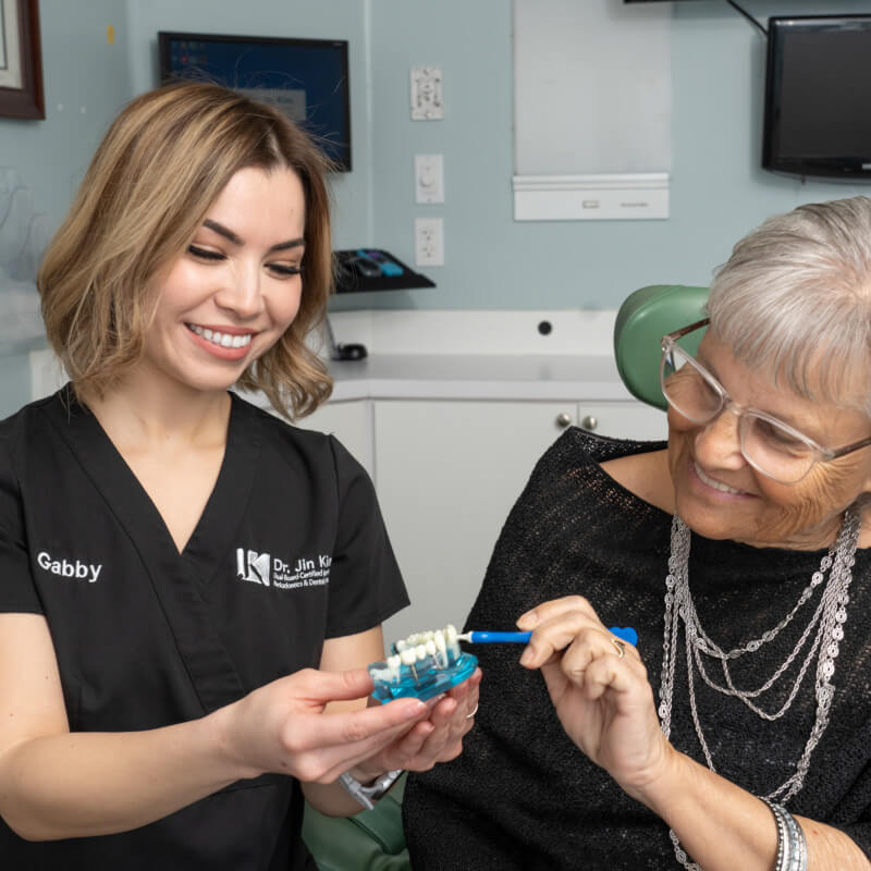 dental hygenist showing patient a tooth model