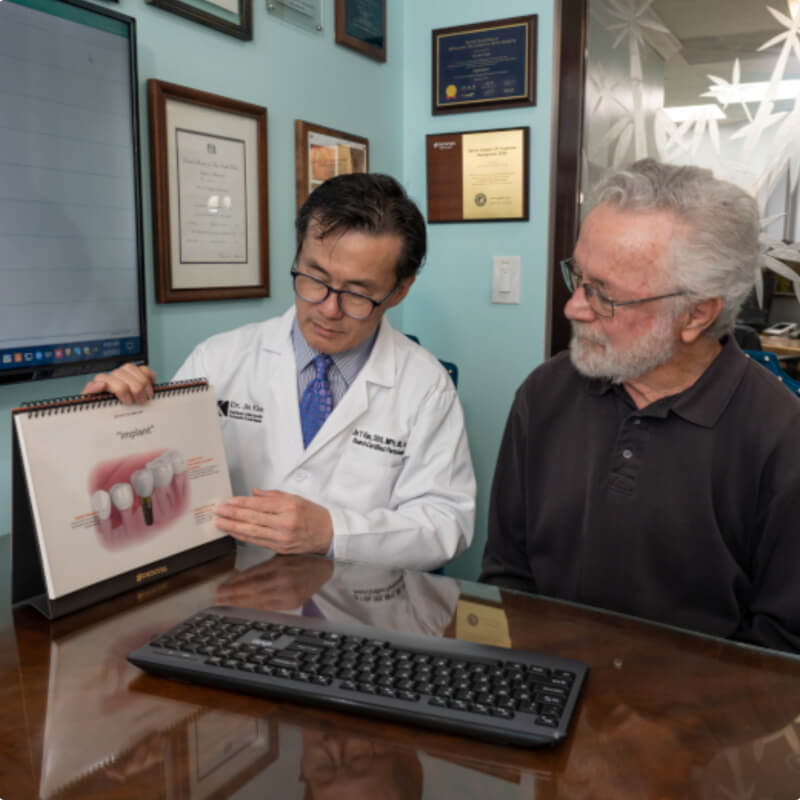 Dr. Jin Kim showing patient dental implant infograpic