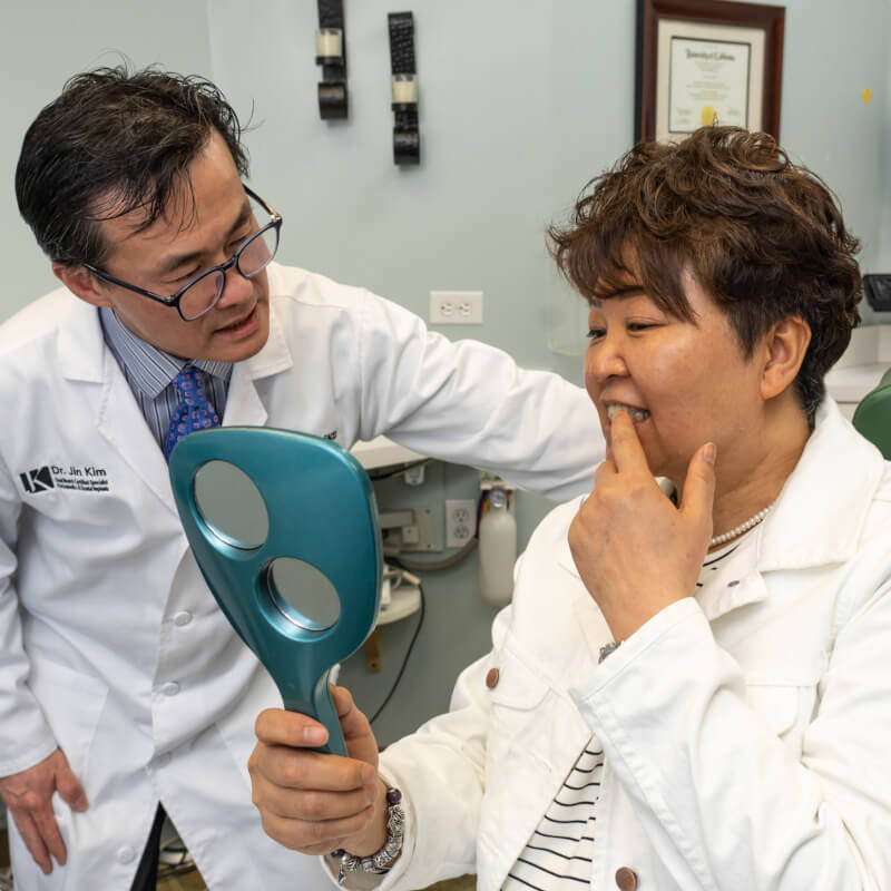 Dr. Jin Kim showing patient teeth with hand mirror